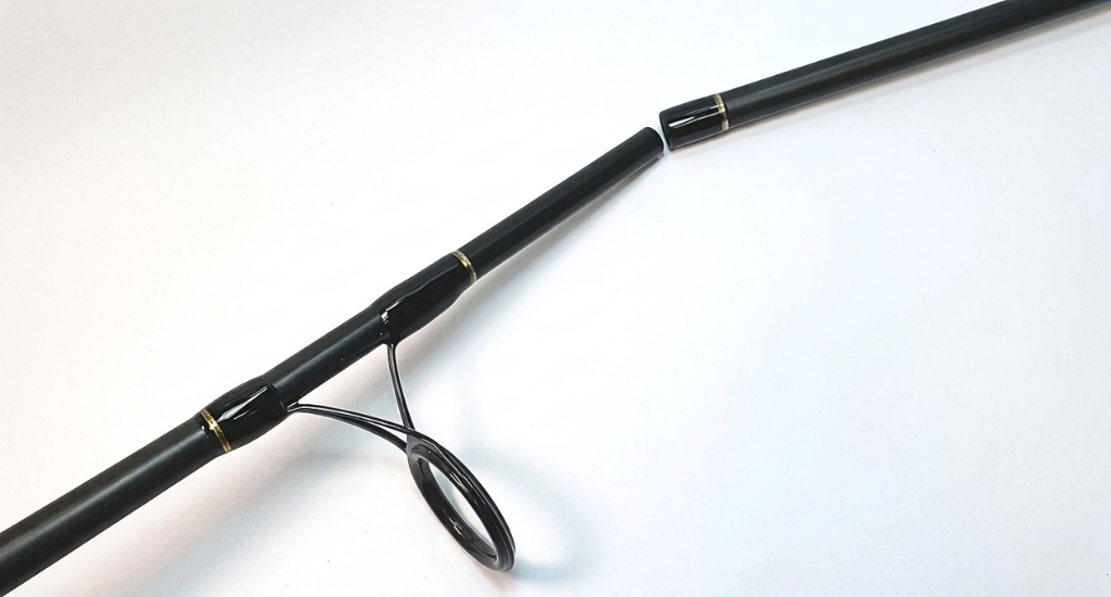 A close-up view showing the separate sections of a black two-piece fishing rod at the ferrule connection joint.