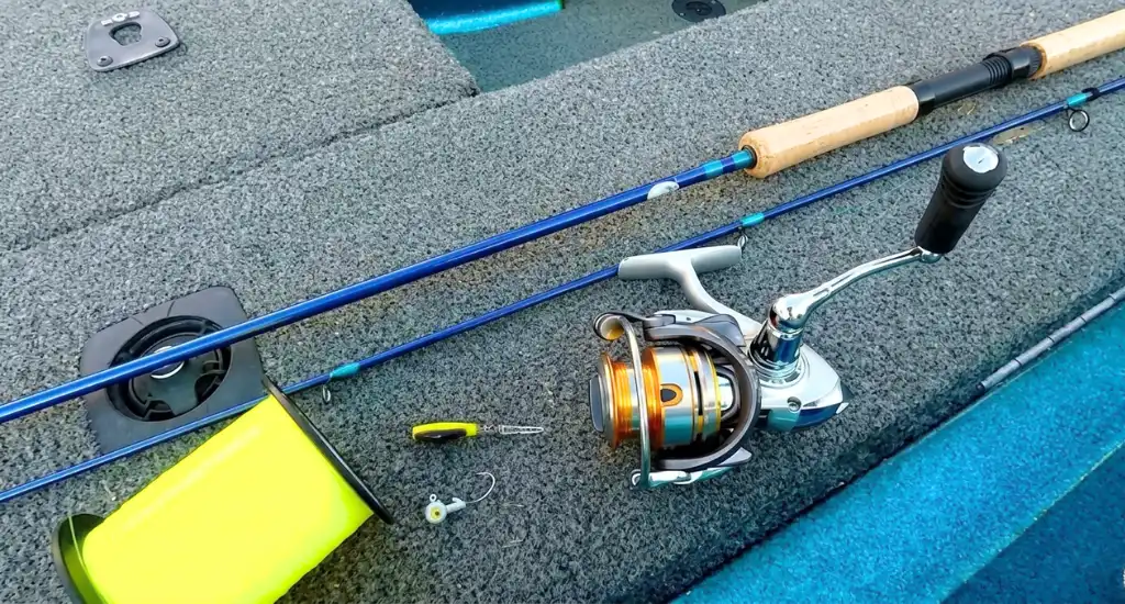 Silver and gold spinning reel attached to a blue fishing rod next to yellow fishing line on a boat carpet.
